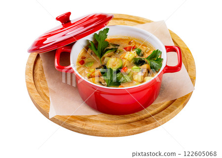 Red pot of healthy vegetarian soup with potatoes, squash, carrot and romatoes served at a wooden board isolated at white background. 122605068