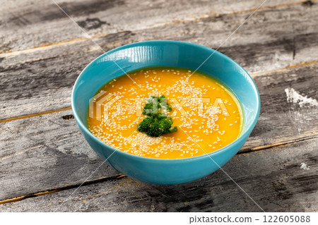 Closeup bowl of pumpkin soup decorated with parsley and sesame at wooden table background. Concept of healthy lifestyle. 122605088