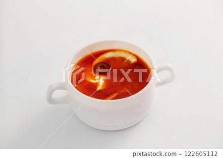 Plate with traditional red Russian soup solyanka with olives and lemon isolated at white background. 122605112