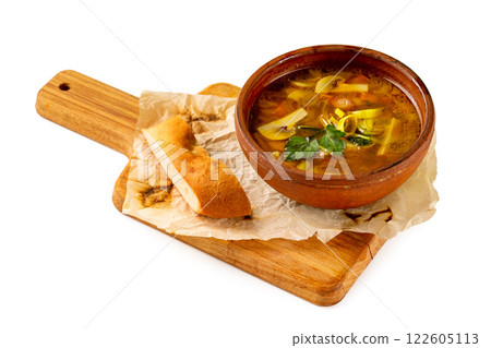 Clay pot of shchi soup with cabbage and mushrooms served with a slice of bread at wooden tray isolated at white background. 122605113