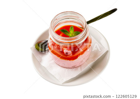 Closeup jar of italian dessert panna cotta with strawberry served with a spoon on a plate isolated at white background. 122605129