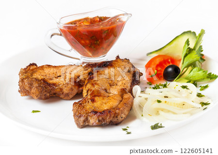 Grilled pork shashlik with red spicy sauce and vegetables on plate isolated  at white background. 122605141