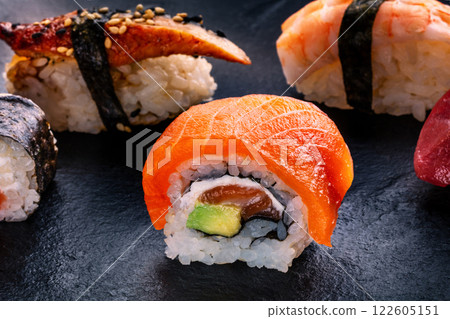 Sushi rolls on a black background. Uramaki with salmon and avocado Sushi rolls on a black background. Uramaki with salmon and avocado 122605151