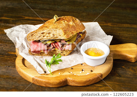 Closeup image of sandwich with meat and cucumbers at wooden board background. Closeup image of sandwich with meat and cucumbers at wooden board background. 122605223