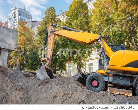 Excavator at work on a sunny day in an urban construction site. Copy space. 122605343