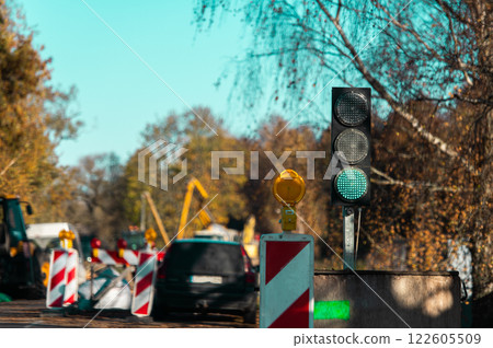 Green light at the traffic light and road repair equipment in the blurred background Green light at the traffic light and road repair equipment in the blurred background 122605509