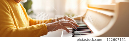 elderly person playing piano in cozy living room, showcasing their passion for music and creativity. warm sunlight adds serene atmosphere 122607131