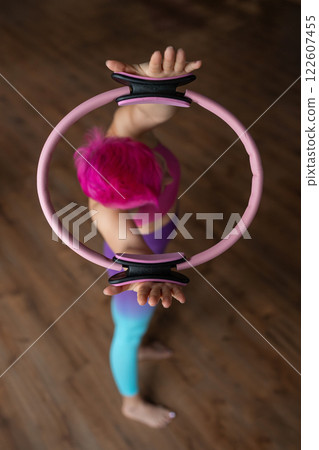 A woman is using a hip Magic Circle at Pilates workout in studio, being active and committed to exercising 122607455