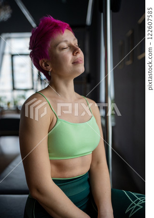 Calm and peaceful woman resting after training in pilates studio. A woman is engaging in a Pilates exercise session using Pilates equipment  122607585