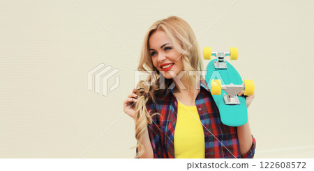 Stylish young blonde woman posing with skateboard on city street 122608572