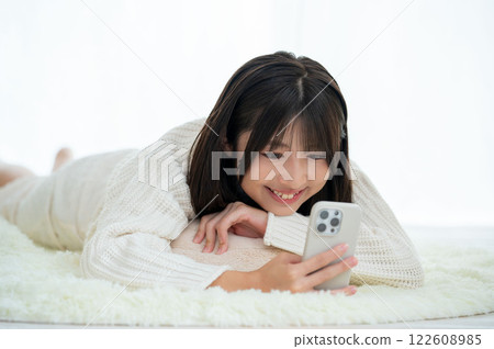 A Japanese woman lying face down and operating a smartphone A Japanese woman lying face down and operating a smartphone 122608985