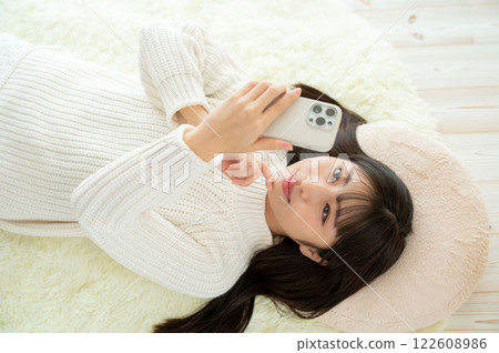 A Japanese woman lying on her back and operating a smartphone A Japanese woman lying on her back and operating a smartphone 122608986