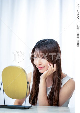 Japanese woman checking her skin in the mirror Japanese woman checking her skin in the mirror 122608999