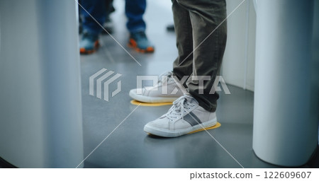 Knee Level Shot of Unrecognizable Passengers Walking Through X-ray Metal Detector Scanning Gates Knee Level Shot of Unrecognizable Passengers Walking Through X-ray Metal Detector Scanning Gates 122609607