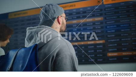 Man Looking for Flight at Arrival and Departure Information Display, Using Smartphone Man Looking for Flight at Arrival and Departure Information Display, Using Smartphone 122609609