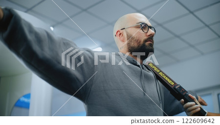 Airport Terminal: Security Officer Checks Passenger Body Using Metal Detector 122609642