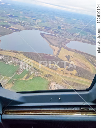 Aerial view from plane window: patchwork fields, lake, and small town under sky. High quality photo Aerial view from plane window: patchwork fields, lake, and small town under sky. High quality photo 122610104