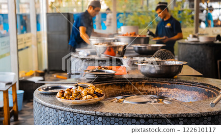 The concept of oriental cuisine. Assorted Uzbek food set, pilaf, samsa, lagman, manta, shurpa central asia food. Homemade Uzbek pilaf or plov from lamb served in cast iron cookware 122610117