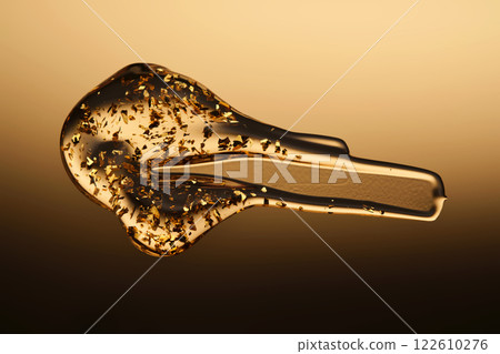 A delicious drop of 24k gold serum on a gold background. A delicious drop of 24k gold serum on a gold background. 122610276
