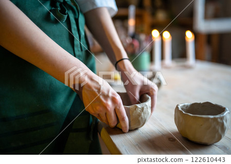 Woman potter hands mold clay bowl, carefully deepening bottom. Pottery workshop, clay school class Woman potter hands mold clay bowl, carefully deepening bottom. Pottery workshop, clay school class 122610443