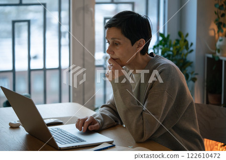 Tired woman overwhelmed by responsibilities, scrolling touchpad while working on laptop at home Tired woman overwhelmed by responsibilities, scrolling touchpad while working on laptop at home 122610472