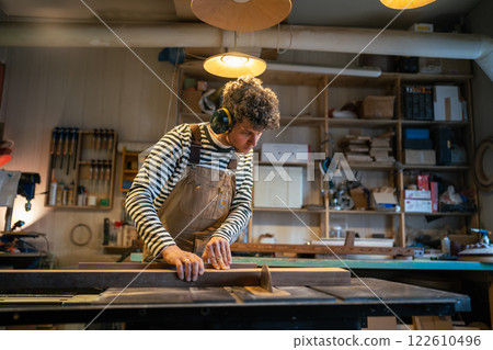 Dedicated male joiner works with circular saw, slicing wooden block with precision. Noise protection Dedicated male joiner works with circular saw, slicing wooden block with precision. Noise protection 122610496