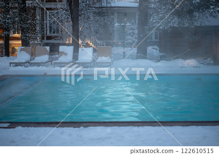 Open-air swimming pool with warm water, loungers in cold weather. Winter wellness spa resort .  122610515