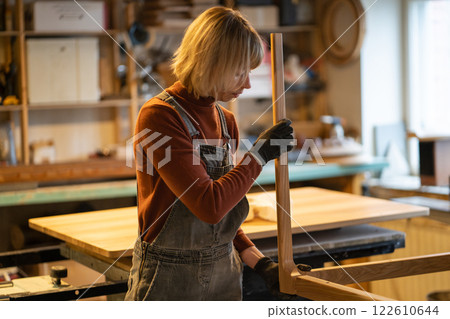 Craftswoman works on wooden table base assembly in carpentry workshop. Production and business 122610644