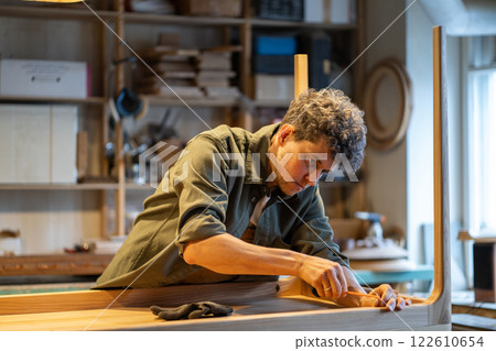 Passionate woodworker attaching nuts and bolts with screwdriver to secure tabletop and legs 122610654