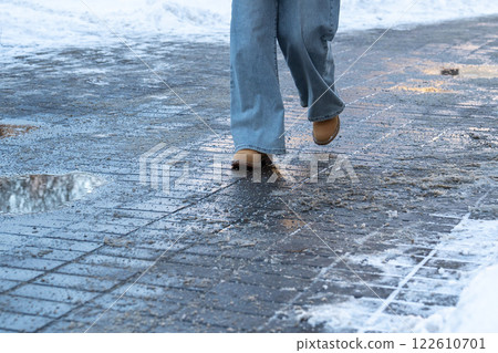 Anti-icing chemicals. Woman walking on the street treated with technical salt or de-icing chemicals 122610701