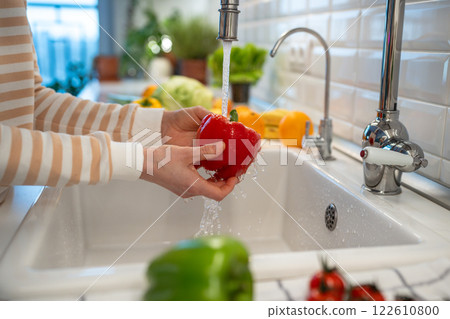 Fresh red peppers paprika washing with hand at home kitchen for healthy eating. Vegan raw cuisine 122610800