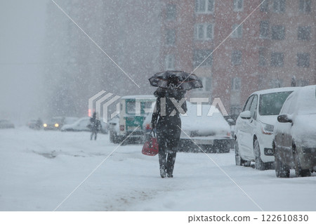 Person with umbrella outdoors during heavy snowfall, winter bad weather and people concept.  122610830
