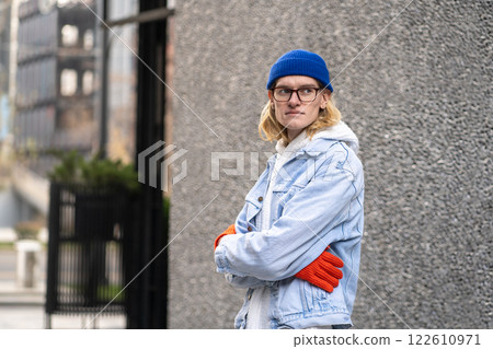 City portrait of stylish guy with arms crossed, standing near wall, waiting, looking into distance 122610971