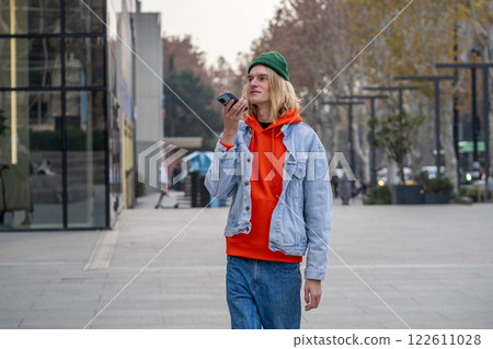 Carefree guy looking like tourist, international student walking in city, speaking over mobile phone Carefree guy looking like tourist, international student walking in city, speaking over mobile phone 122611028