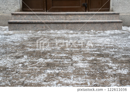 Slippery sidewalk covered with thick crust of ice in front of entrance to the building. Winter time. 122611036