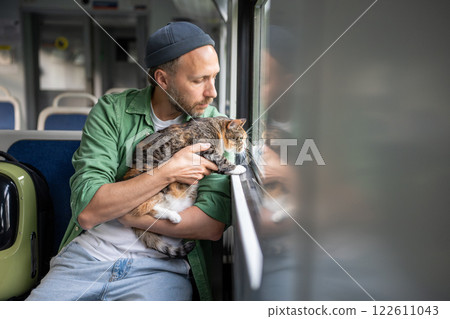 Caring man traveling on electric train with curious cat sitting calmly on owner lap looking window. Caring man traveling on electric train with curious cat sitting calmly on owner lap looking window. 122611043