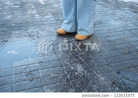 Legs in boots stand on salted sidewalk, walk carefully on winter chill. Frosty path, ice prevention Legs in boots stand on salted sidewalk, walk carefully on winter chill. Frosty path, ice prevention 122611075