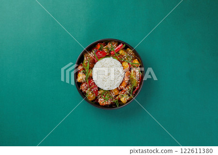 top shot on blue background black salad plate with Chinese rice and chicken in sweet and sour sauce with pineapples Asian cuisine healthy eating top shot on blue background black salad plate with Chinese rice and chicken in sweet and sour sauce with pineapples Asian cuisine healthy eating 122611380
