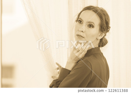 woman looking through window waiting woman looking through window waiting 122611388