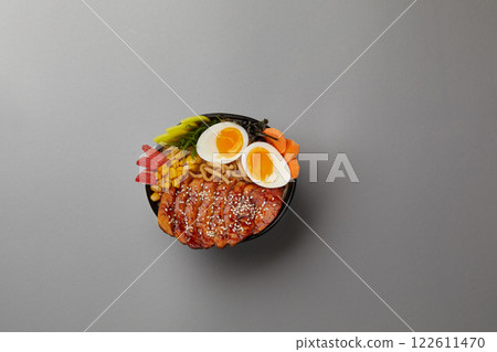 top shot on gray background professional kitchen soup black plate with classic ramen with pork boiled eggs nori sheet corn egg noodles with broth Japanese traditional cuisine top shot on gray background professional kitchen soup black plate with classic ramen with pork boiled eggs nori sheet corn egg noodles with broth Japanese traditional cuisine 122611470