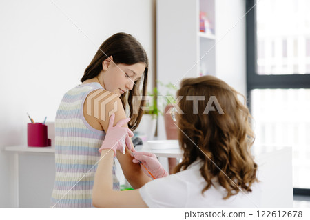 Female doctor, pediatrician injecting vaccine into teenage girl arm. Concept of preventive health care and vaccination for teenagers Female doctor, pediatrician injecting vaccine into teenage girl arm. Concept of preventive health care and vaccination for teenagers 122612678