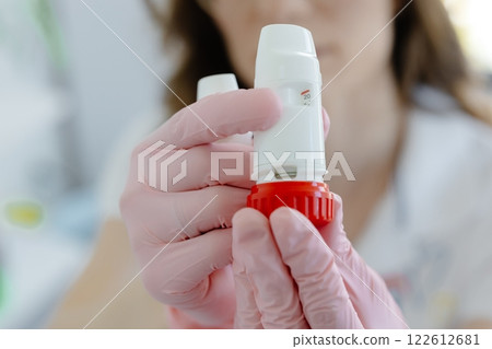 Female doctor holding and showing asthma inhaler. Medical portable equipment for asthma attack Female doctor holding and showing asthma inhaler. Medical portable equipment for asthma attack 122612681