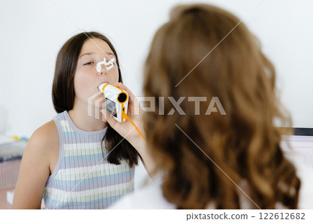 Girl testing breathing function by spirometry in doctors office. Diagnosis of respiratory function in pulmonary disease Girl testing breathing function by spirometry in doctors office. Diagnosis of respiratory function in pulmonary disease 122612682
