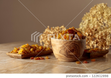 Yellow sultana raisins in a wooden bowl on a beige background. 122612898