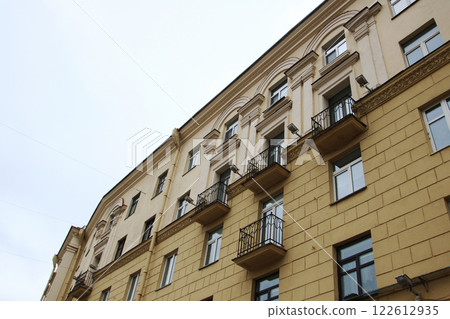 As I gaze upwards at a tall building adorned with numerous windows As I gaze upwards at a tall building adorned with numerous windows 122612935