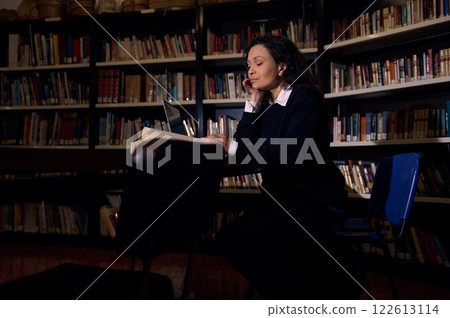 Person Studying in a Library Surrounded by Bookshelves Person Studying in a Library Surrounded by Bookshelves 122613114