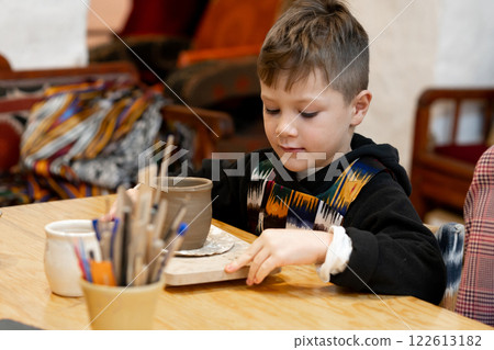 A boy creates a pot in a pottery workshop 122613182