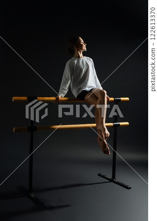 Expressive dance pose of girl at ballet barre in an artistic setting Expressive dance pose of girl at ballet barre in an artistic setting 122613370