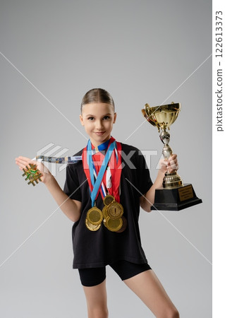 Young dancer shows off her trophies and medals from a great competition Young dancer shows off her trophies and medals from a great competition 122613373