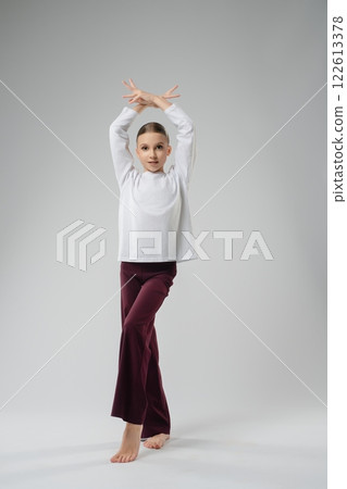 Girl showcases elegant dance pose in artistic setting during performances Girl showcases elegant dance pose in artistic setting during performances 122613378
